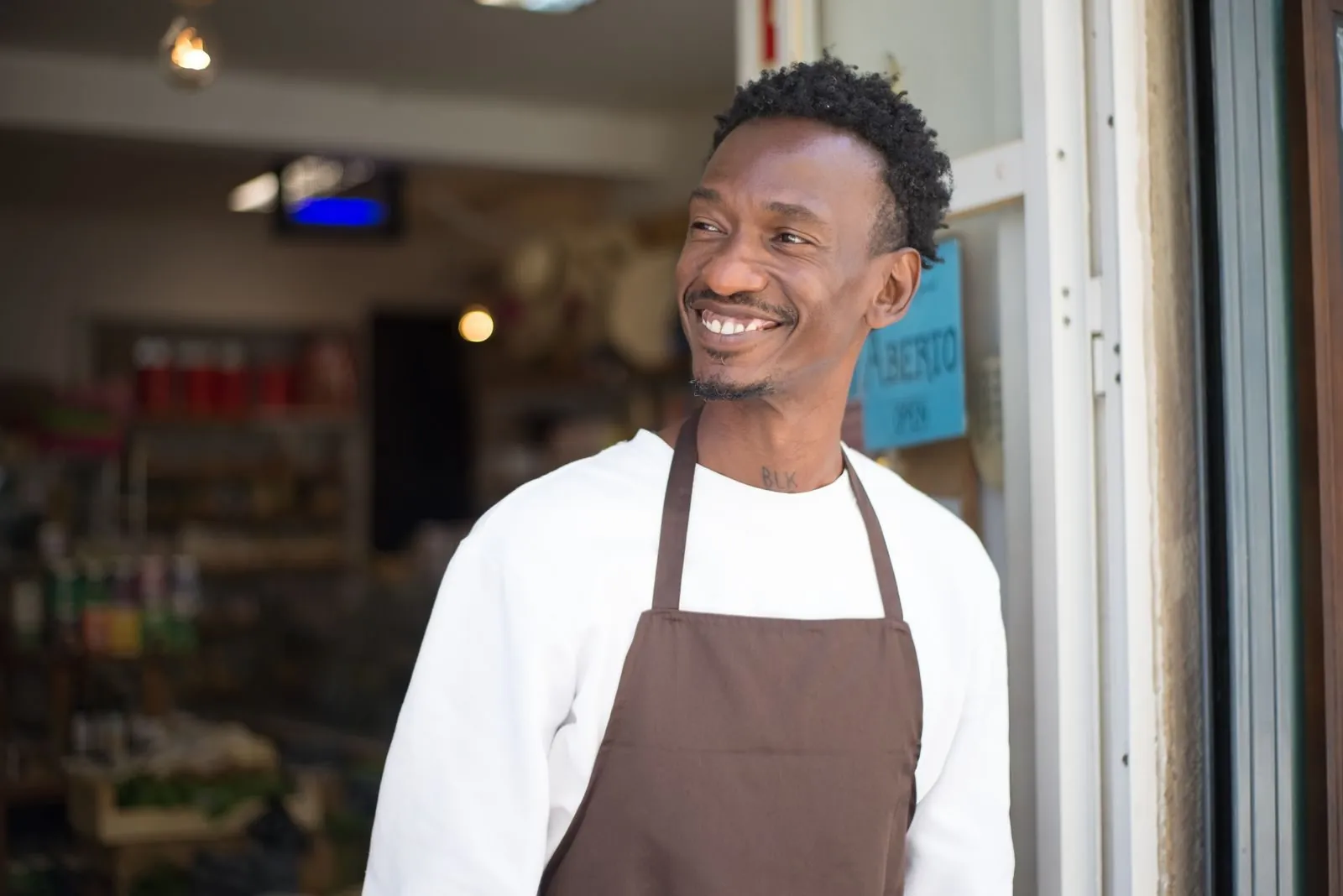 A shopkeeper smiling in the doorway of his store