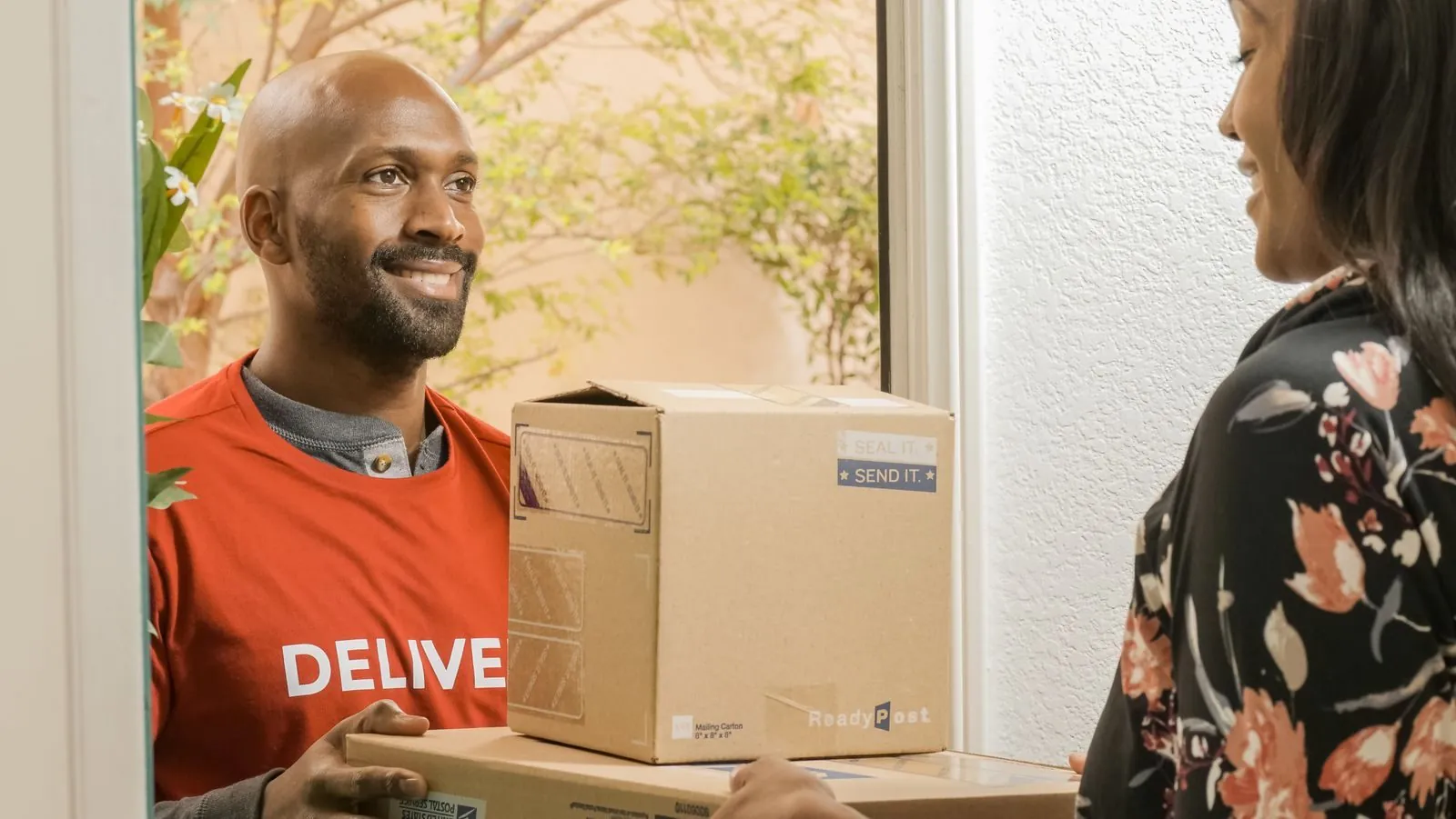 A courier handing a parcel to a customer at her door